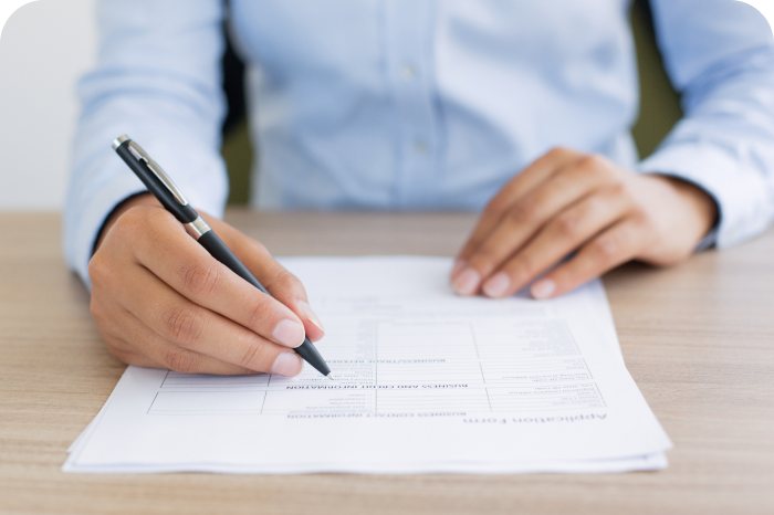 Hands filling in a paper application form